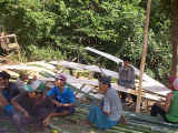 Stripping & flattening bamboo canes to build the teacher's house
