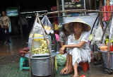 Conical hat topped local sells fruit snacks on the sidewalk